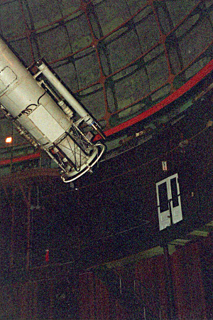 [The bottom edge of the dome with its lattice-like metal inside supports are visible. One end of the long metal tube holding the lenses is visible and is somewhat close to a double-door opening to a small balcony inside the dome.]